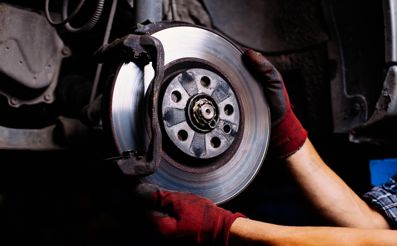 Mechanic in red gloves installing a car brake disc in a garage
