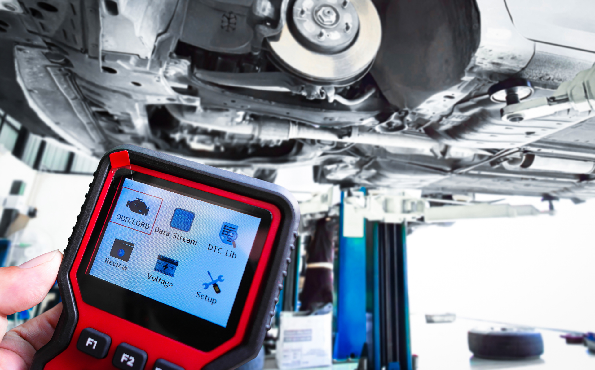 Red diagnostic tablet scanning the underside of a Mercedes vehicle