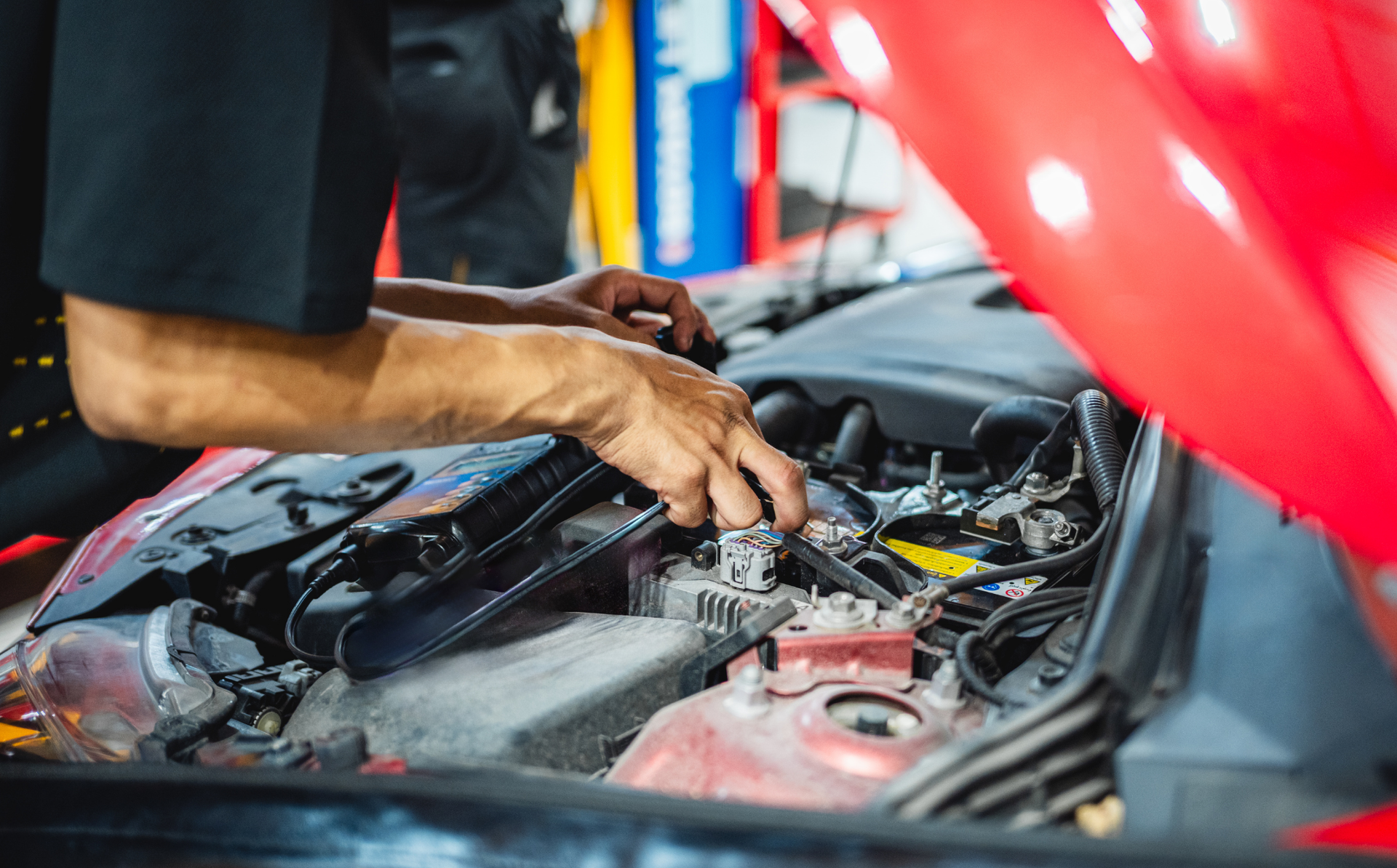 Mechanic working under the hood of a Mercedes-Benz in a repair shop