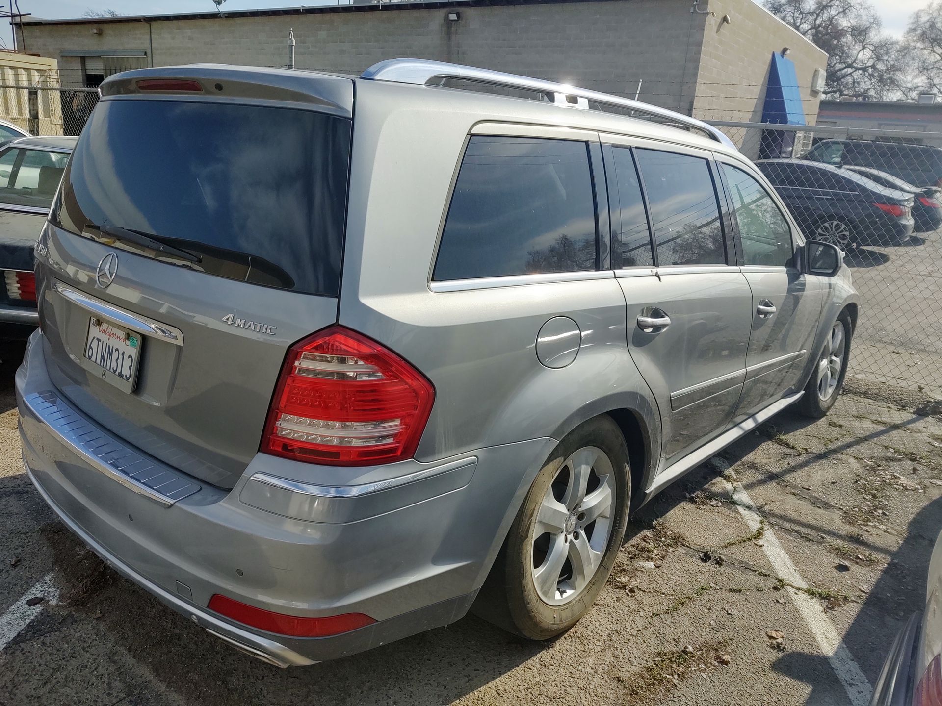 Silver SUV parked outdoors beside a building, seen from the rear-left side.