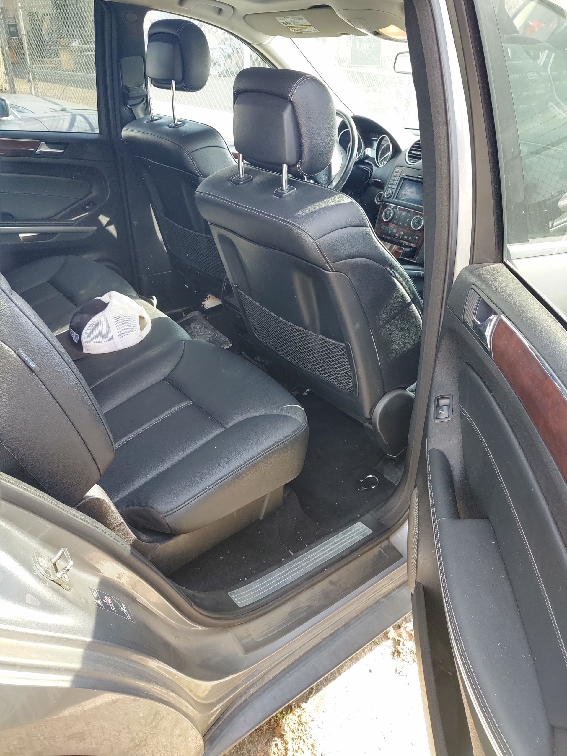 Back seat of a car with black leather seats and a white cup on the rear seat floor