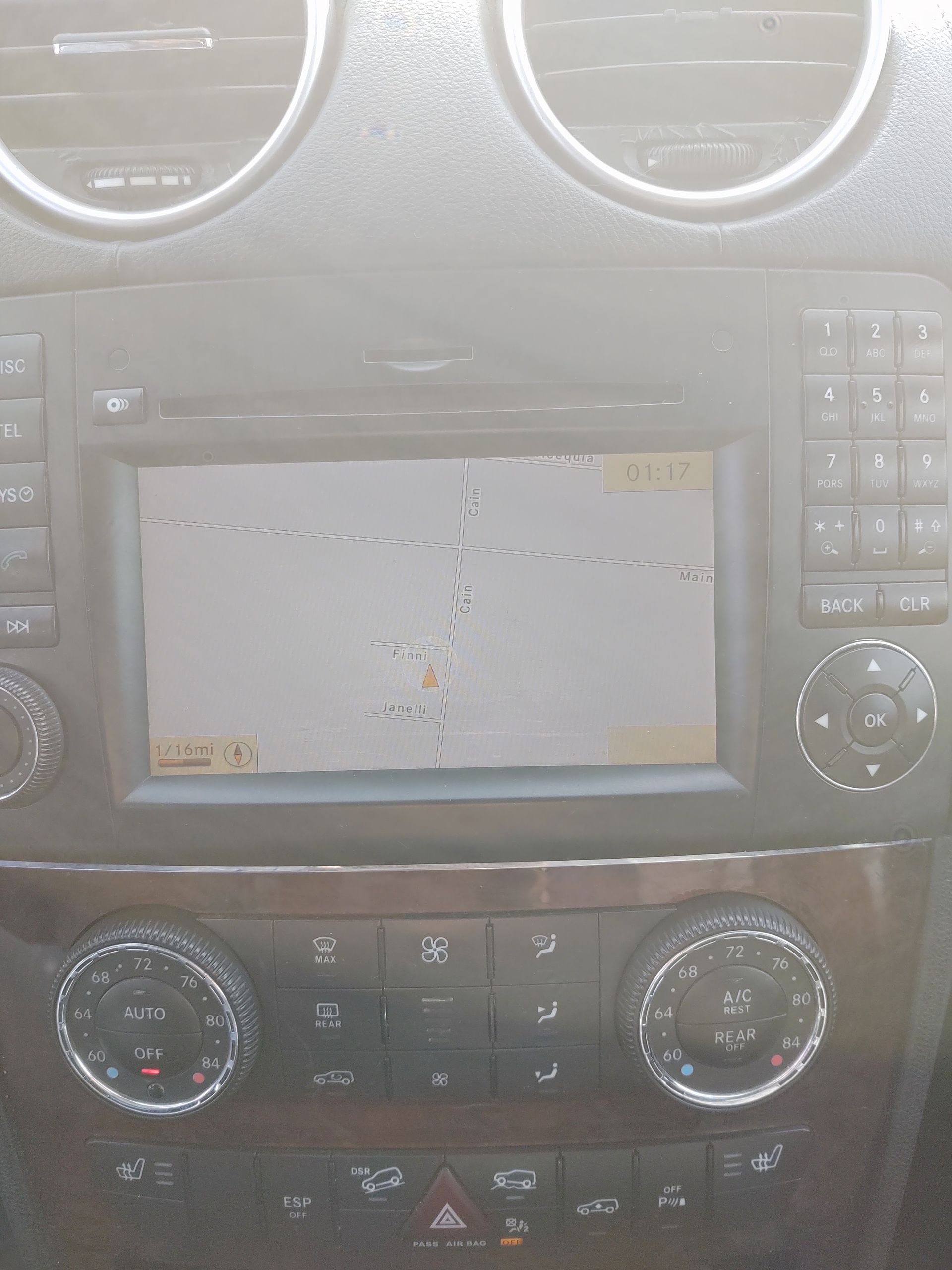 Car dashboard with a cracked center touchscreen and round air vents above climate controls