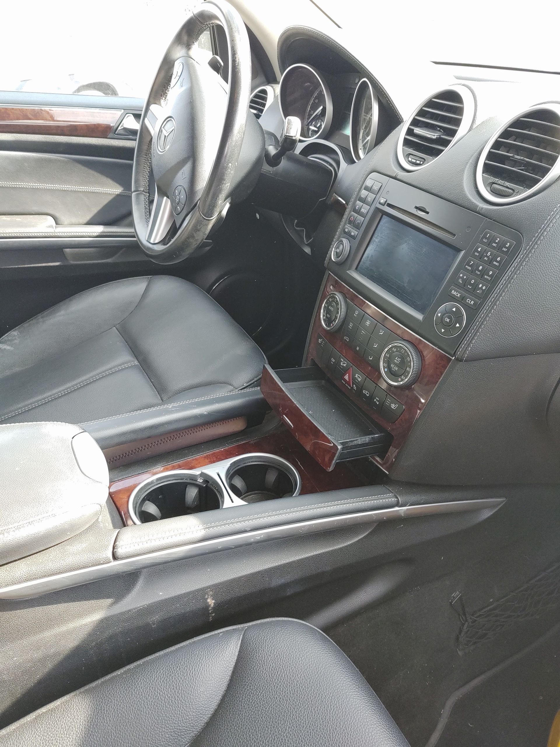 Car interior with steering wheel, center console, cup holders, and dashboard vents in gray and wood trim