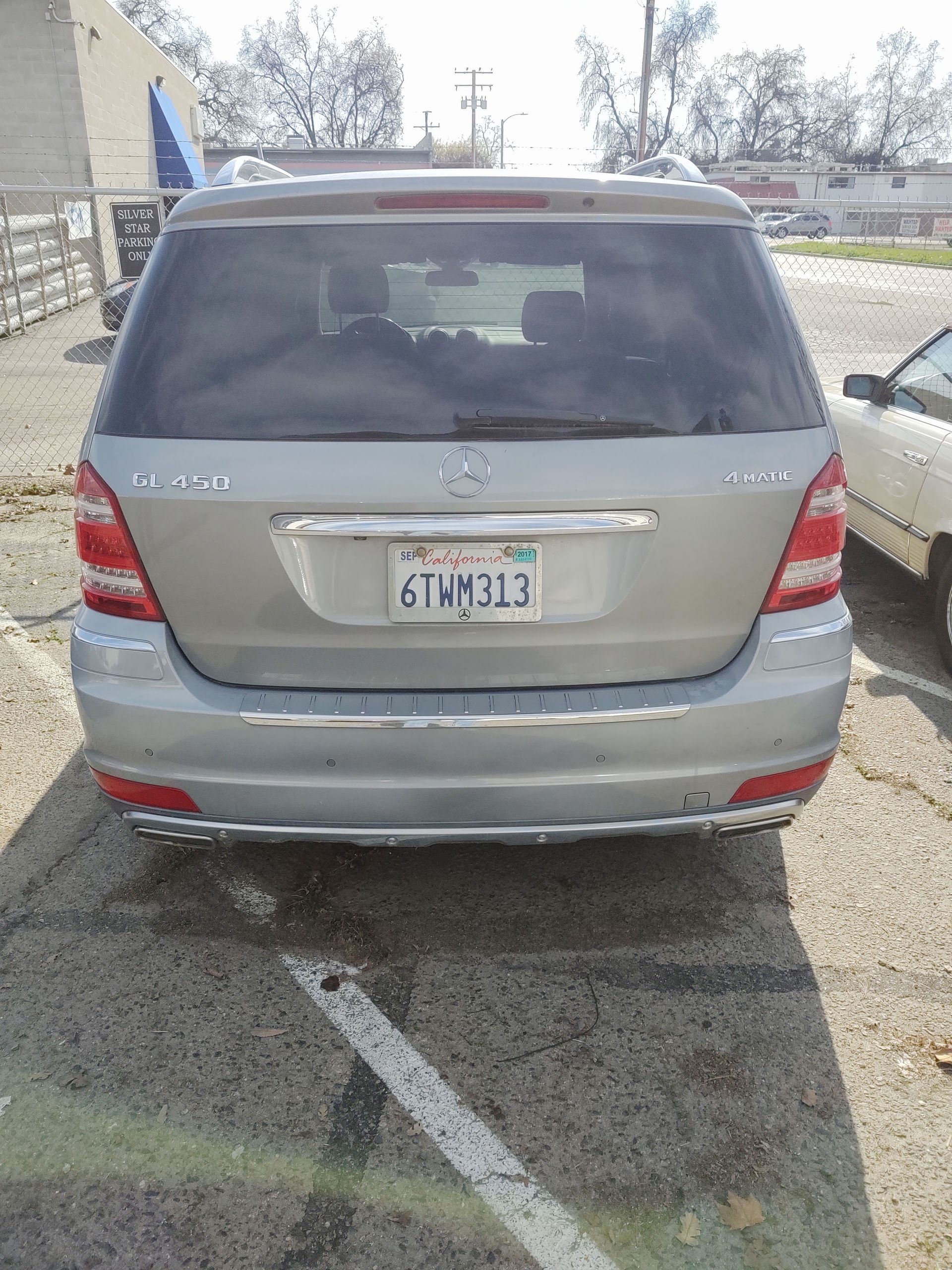 Rear view of a beige minivan parked in a lot, with a visible license plate and empty surroundings.