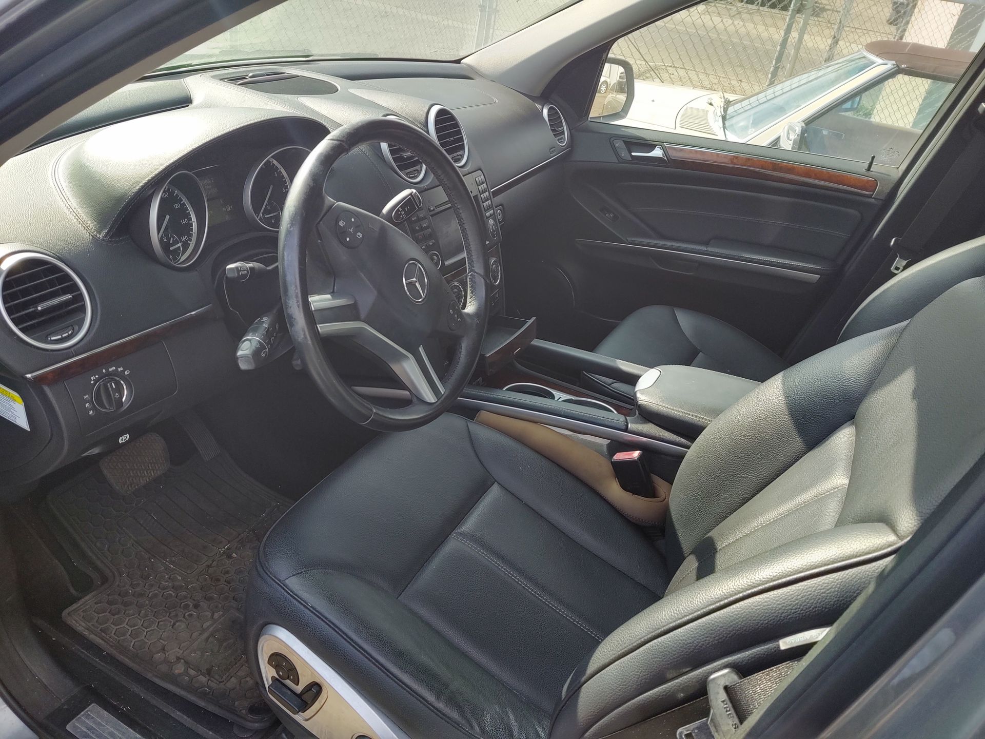 Car interior with black leather seats, steering wheel, dashboard, and center console in daylight