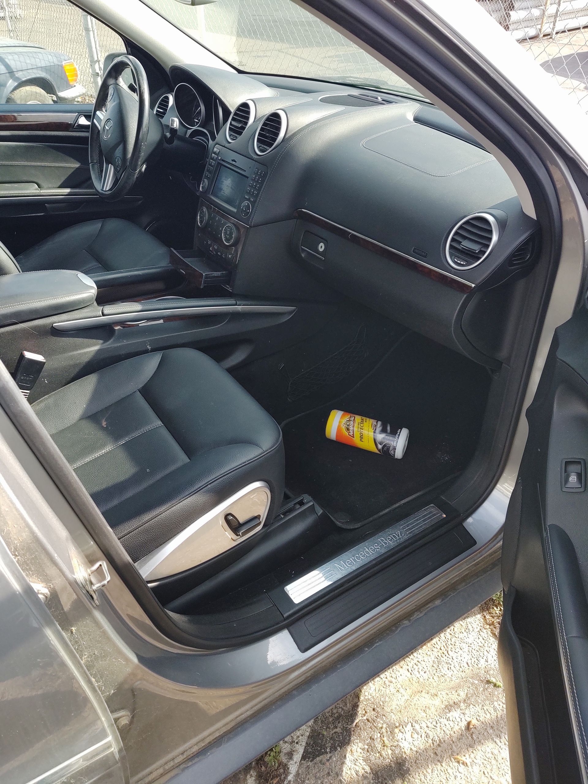 Open car door showing the front passenger seat, dashboard, and a drink can on the floor.