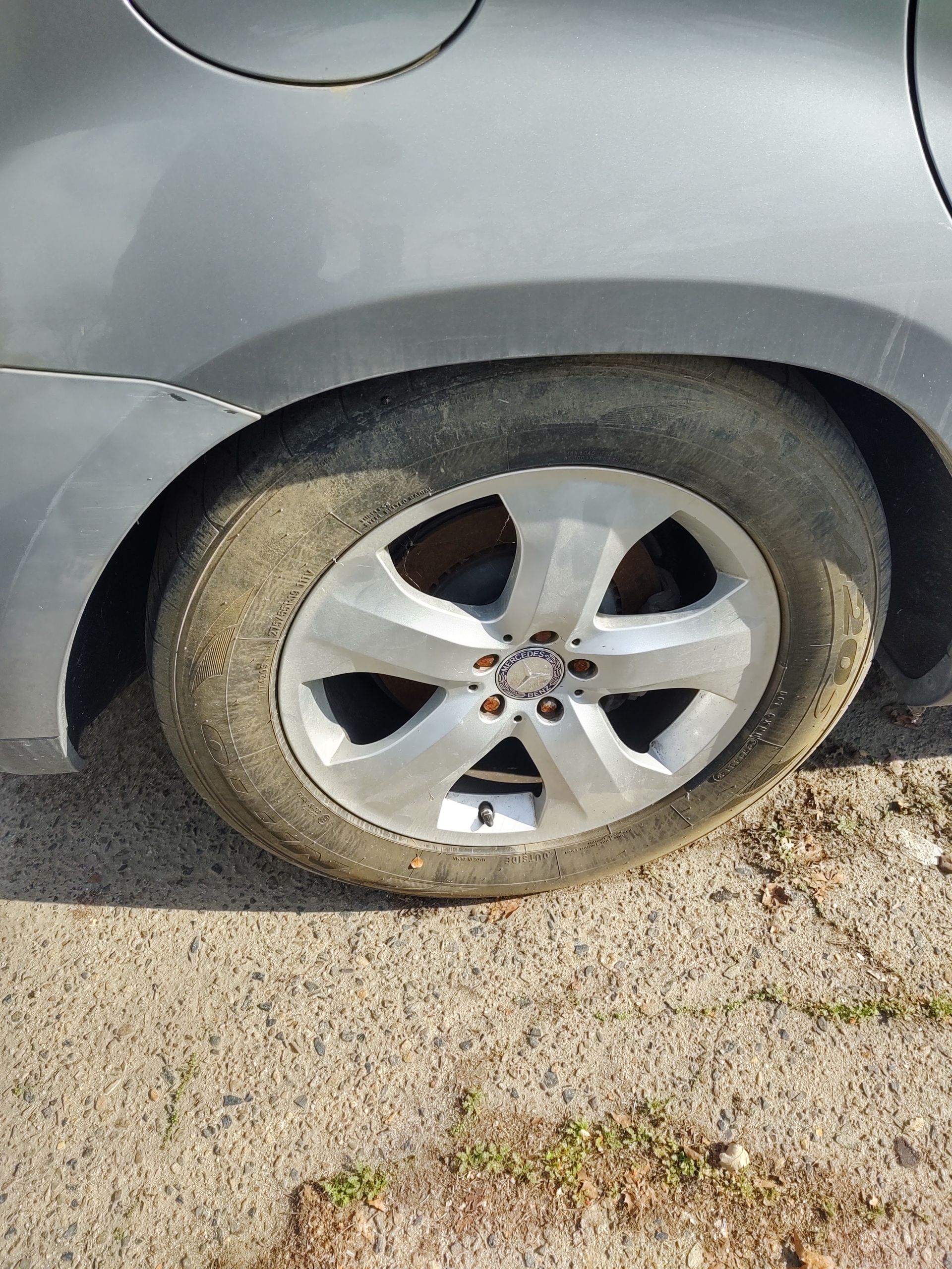 Flat rear car tire on a silver vehicle parked on pavement.
