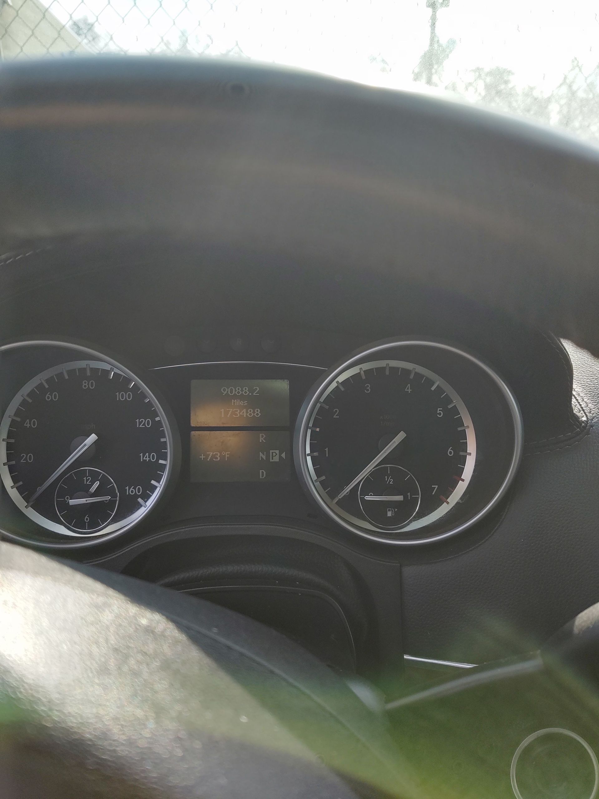 Car dashboard with instrument cluster and sunlight glare on the windshield