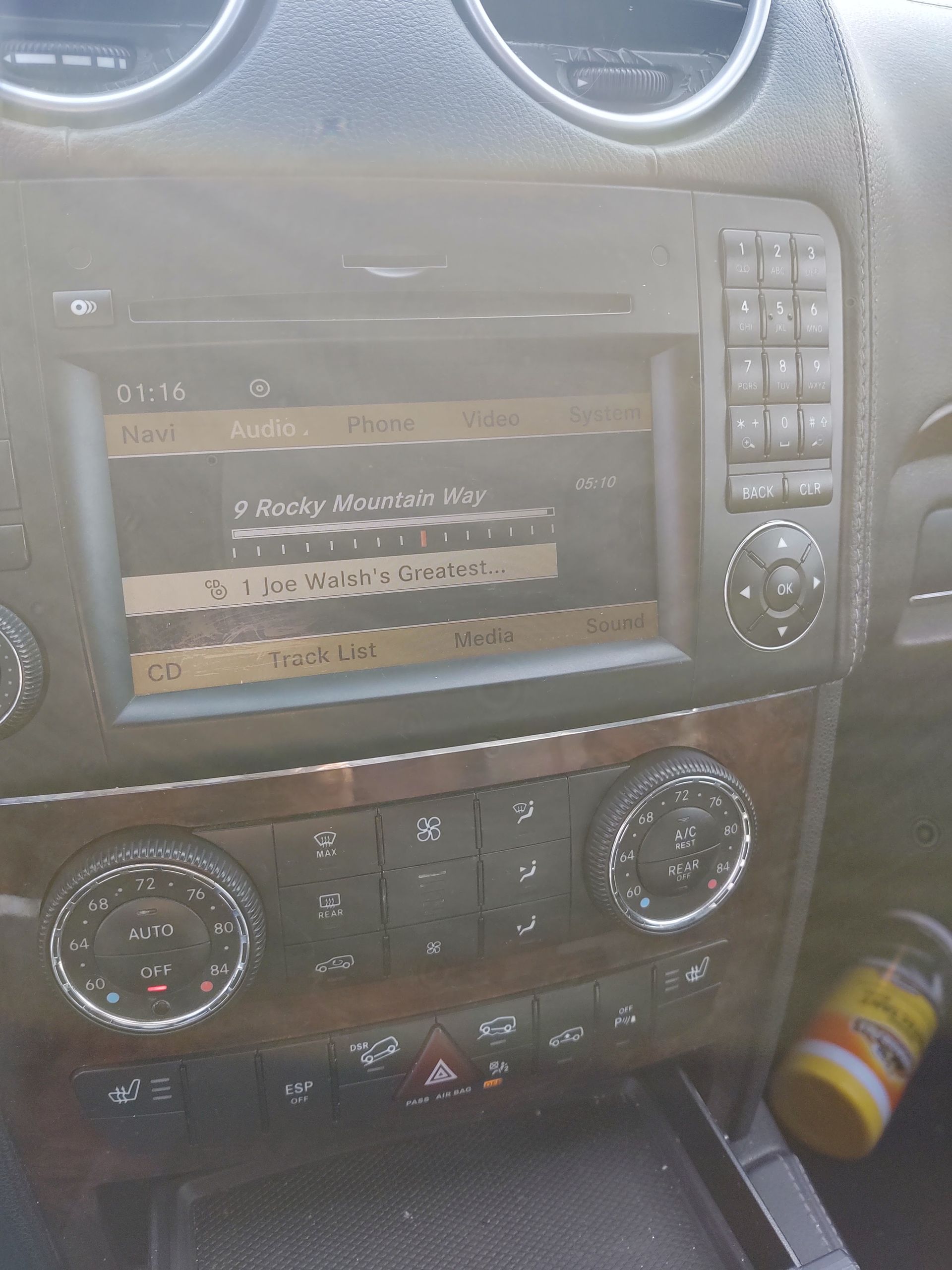Car dashboard with a stereo display, climate controls, and buttons, photographed from the driver’s seat.