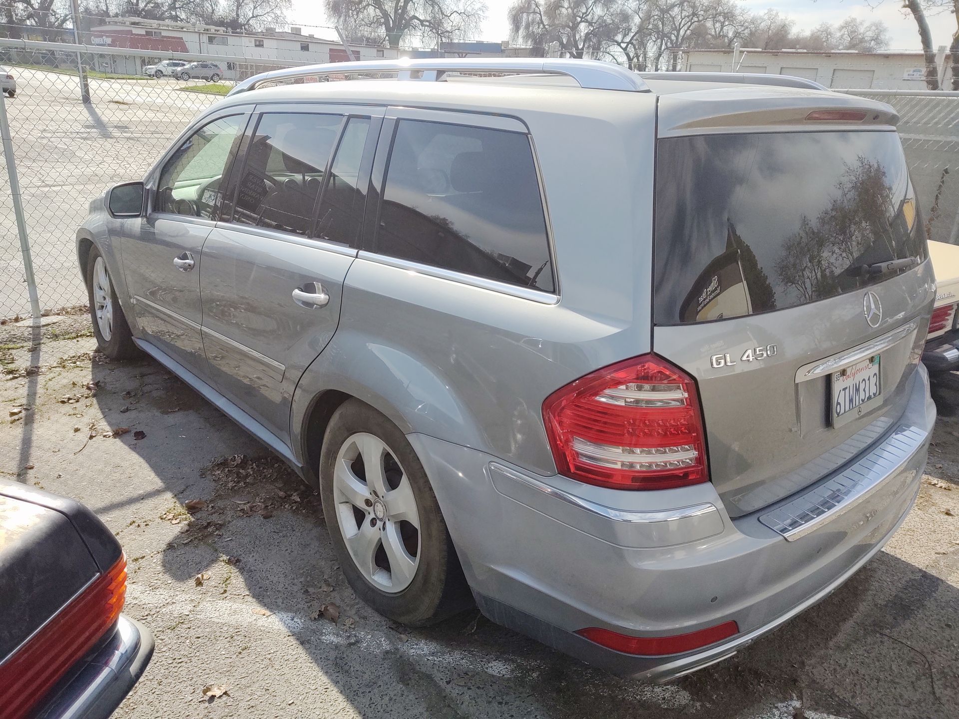 Silver minivan parked in a lot, rear three-quarter view with tinted windows and red taillights.