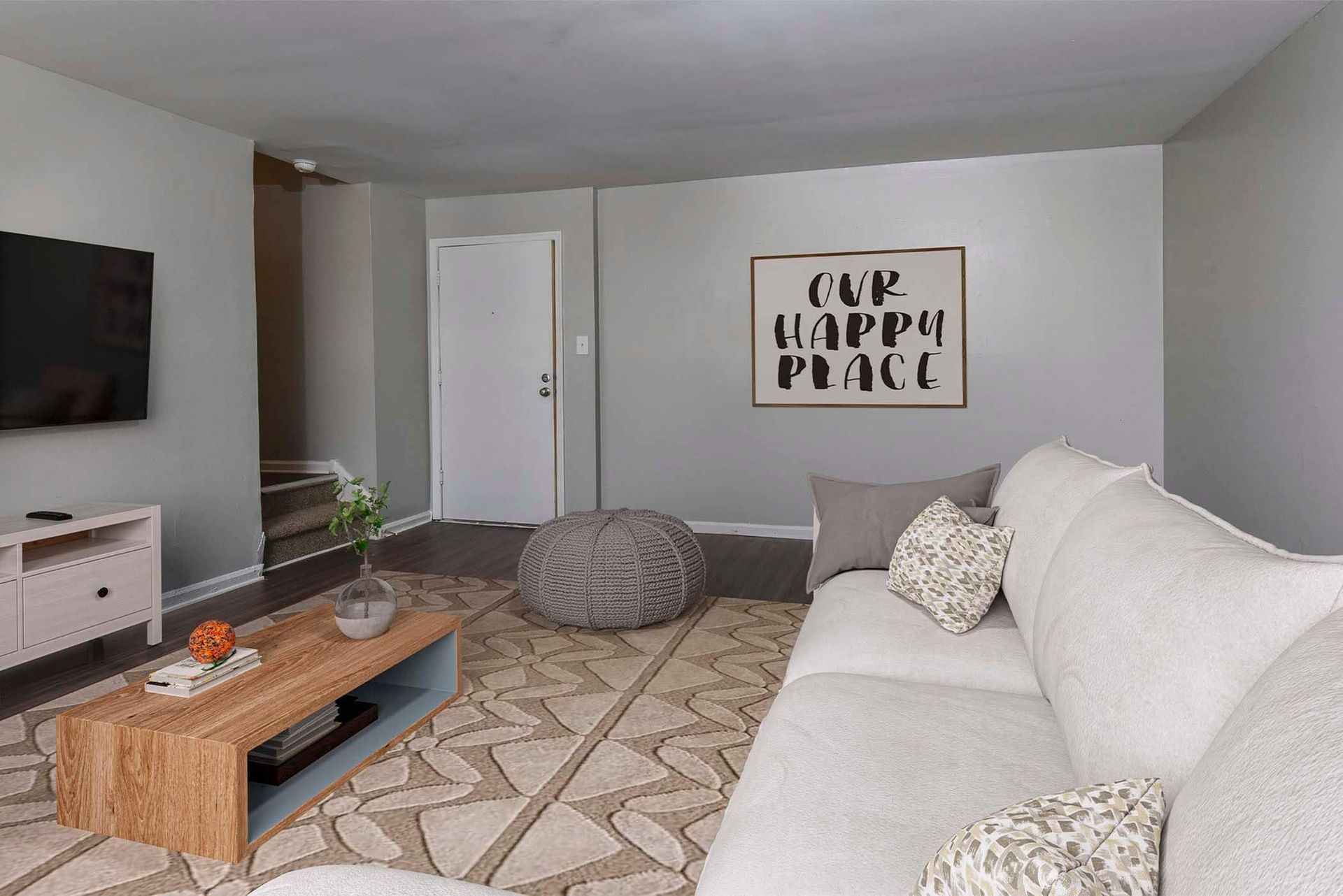 Living room in an apartment with gray walls, a white sectional sofa, coffee table, and wall art.