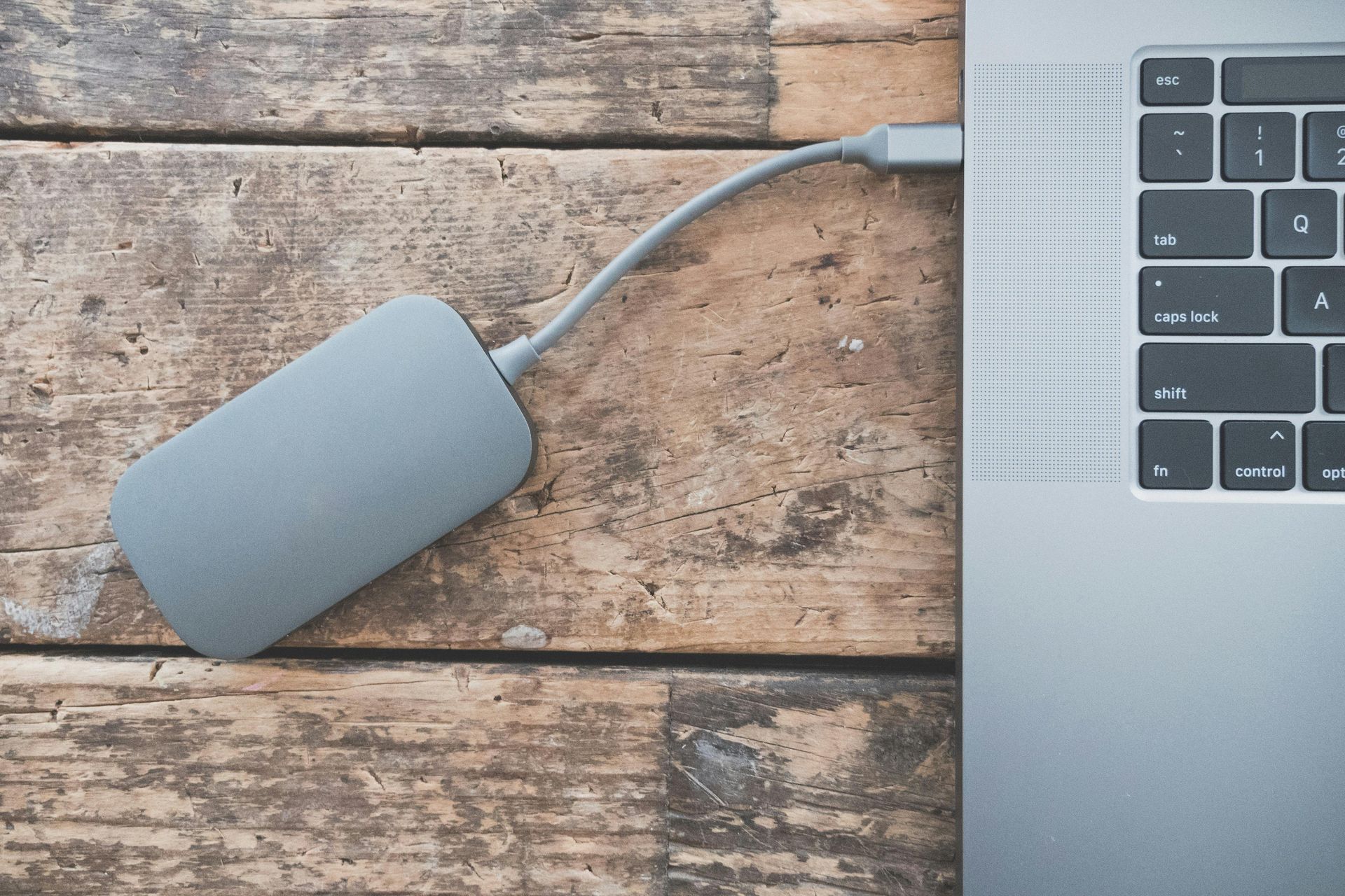 Een harde schijf is aangesloten op een laptop op een houten tafel.