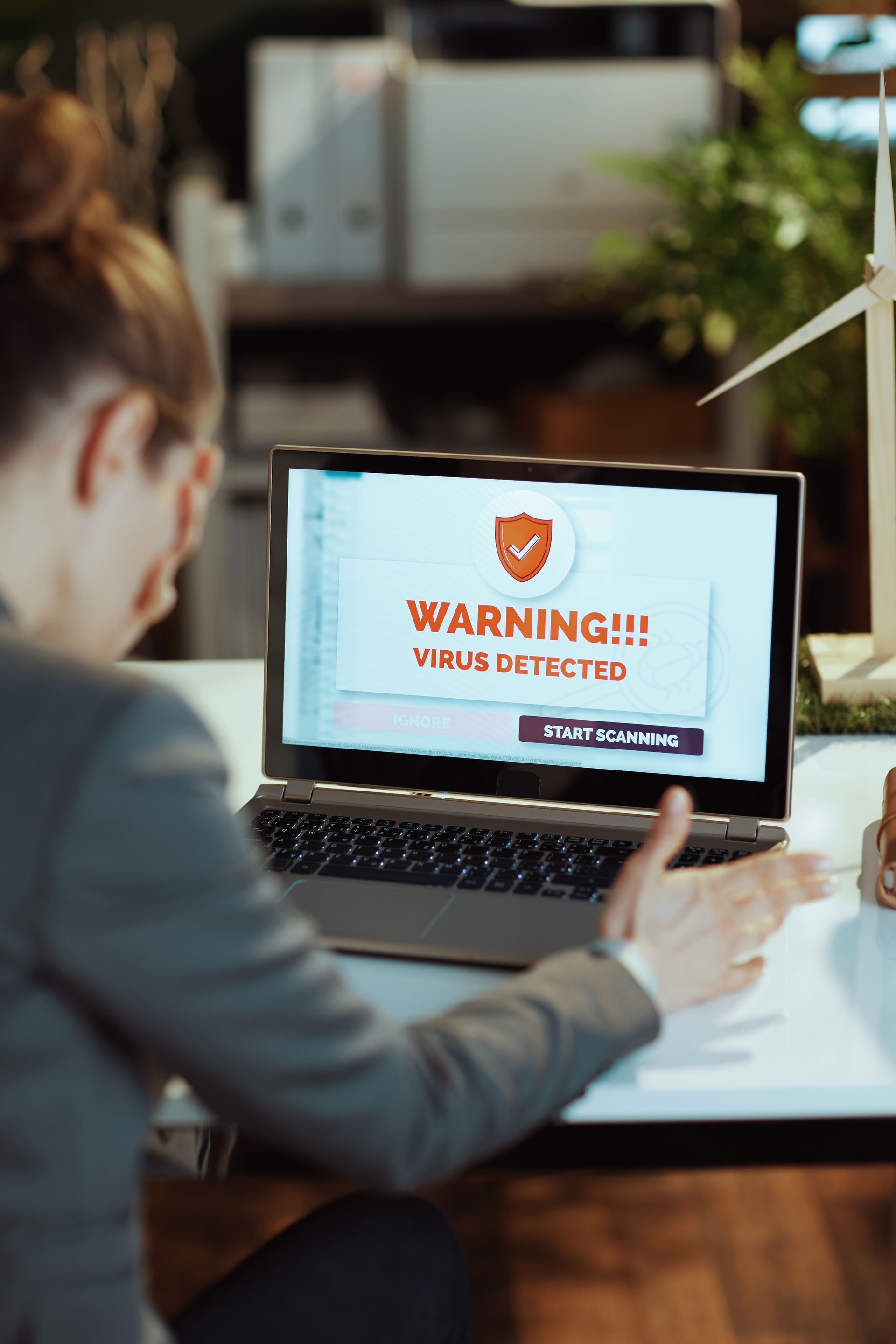Een vrouw zit aan een bureau en gebruikt een laptopcomputer.