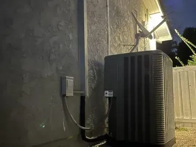 A black air conditioner is sitting on the side of a building.