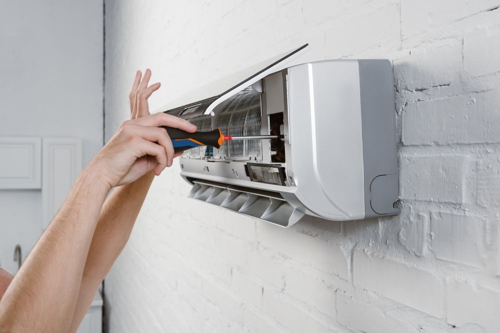 Hands Of A Person Repairing An Air Conditioner Unit — Electrical & Air Cooling Solutions in Townsville, QLD