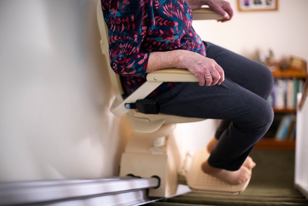 Person Seated On A Stairlift Ascending A Staircase — Electrical & Air Cooling Solutions in Railway Estate, QLD