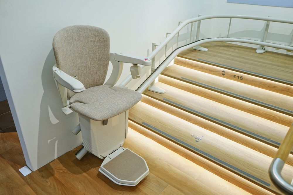 Stairlift On Wooden Stairs With White Walls And Glass Railing — Electrical & Air Cooling Solutions in Charters Towers, QLD