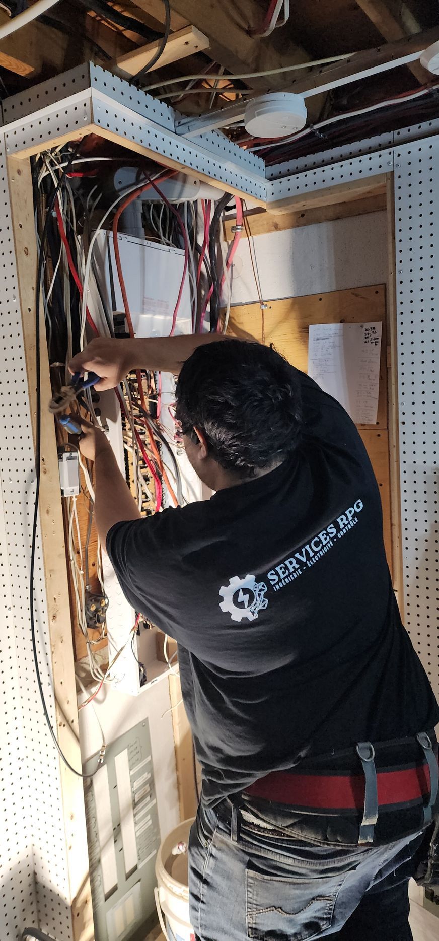 Un électricien travaille sur un tableau électrique dans un sous-sol.