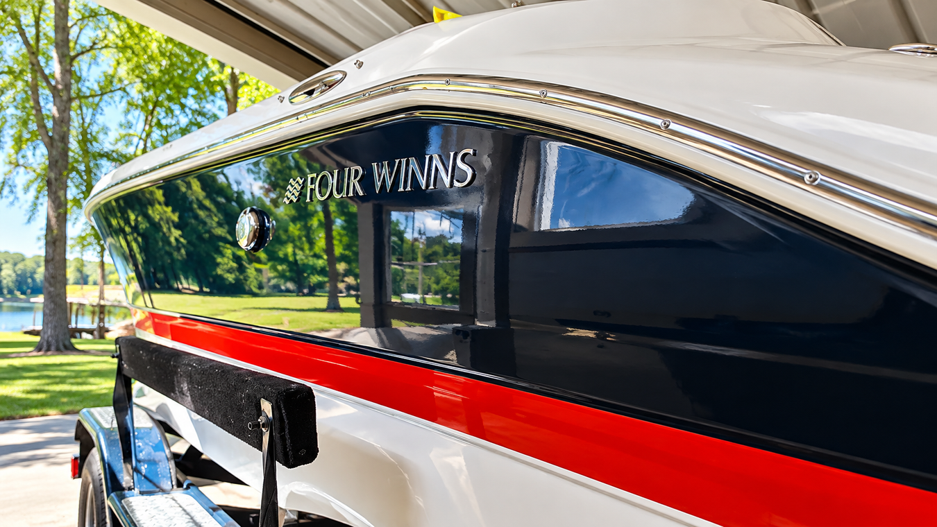 Close-up of a white speedboat with black and red stripes under a canopy by the water