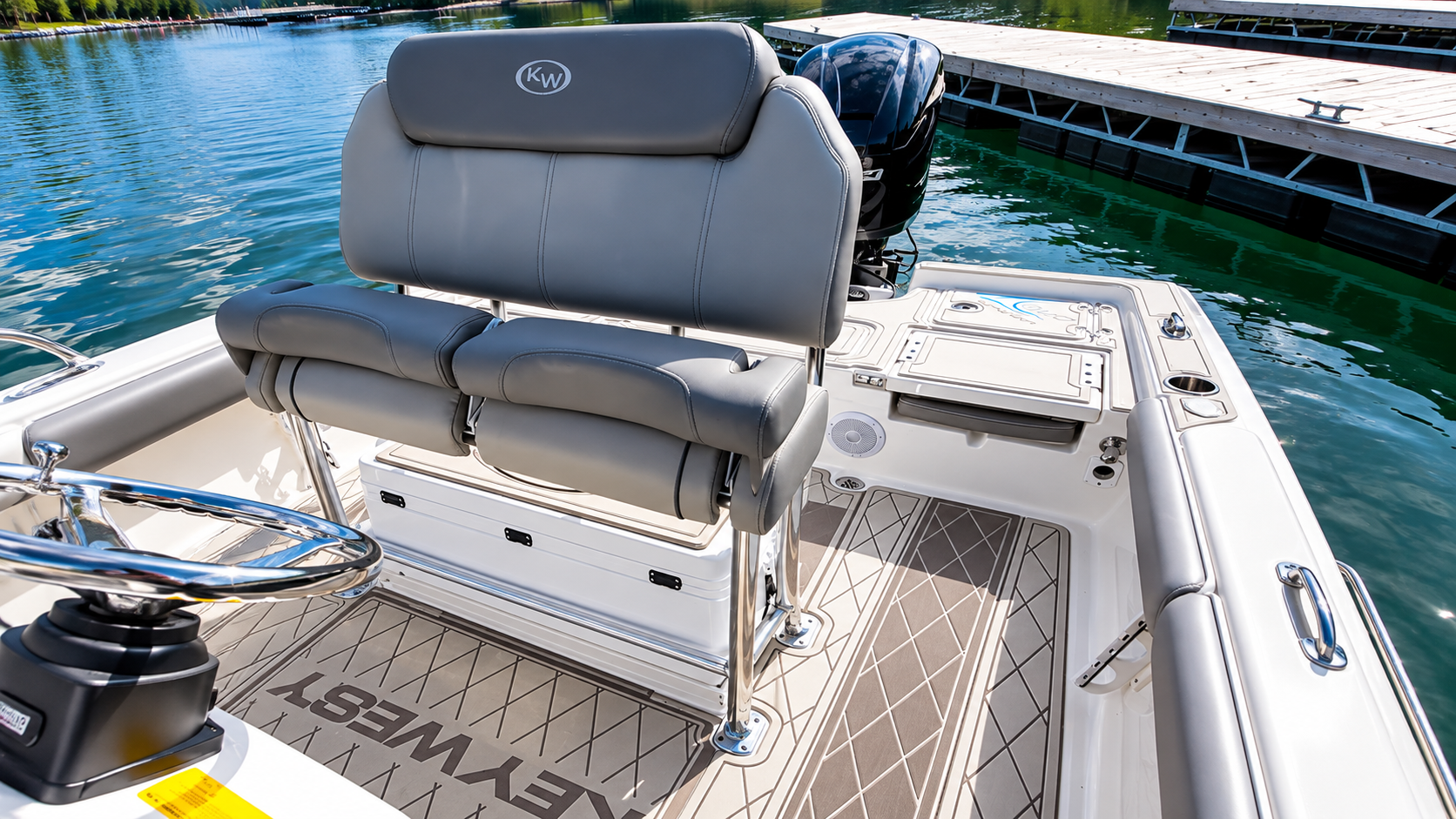 Boat seating area on a docked boat with gray cushioned helm seats and blue water beside it