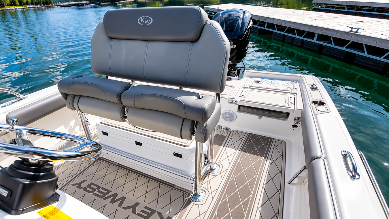 Boat seating area on a docked boat with gray cushioned helm seats and blue water beside it
