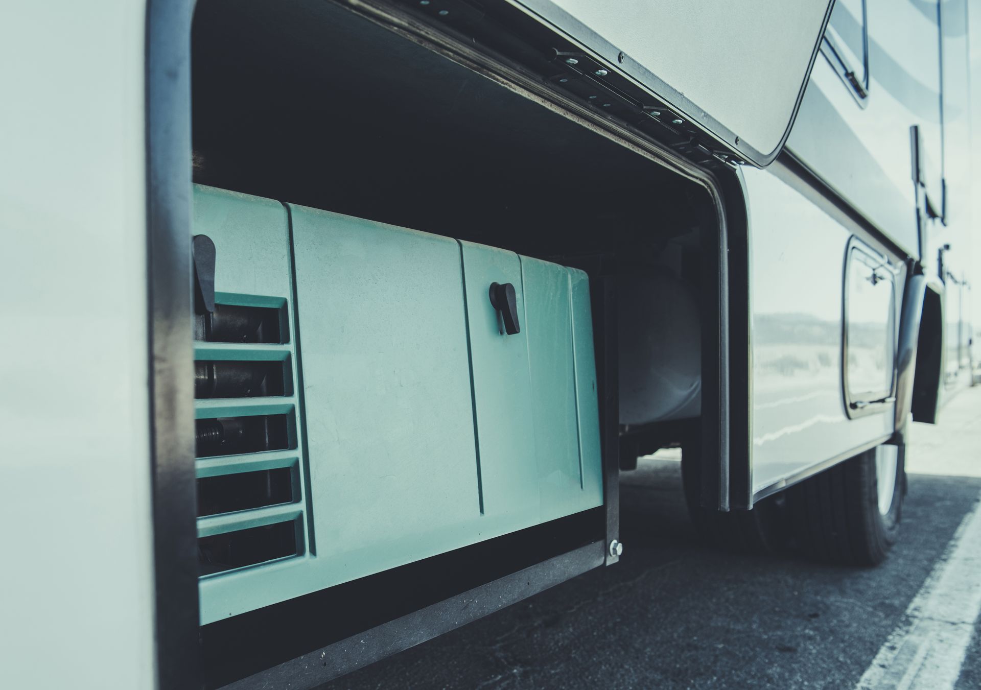 Grey motorhome with open storage compartments parked by the roadside