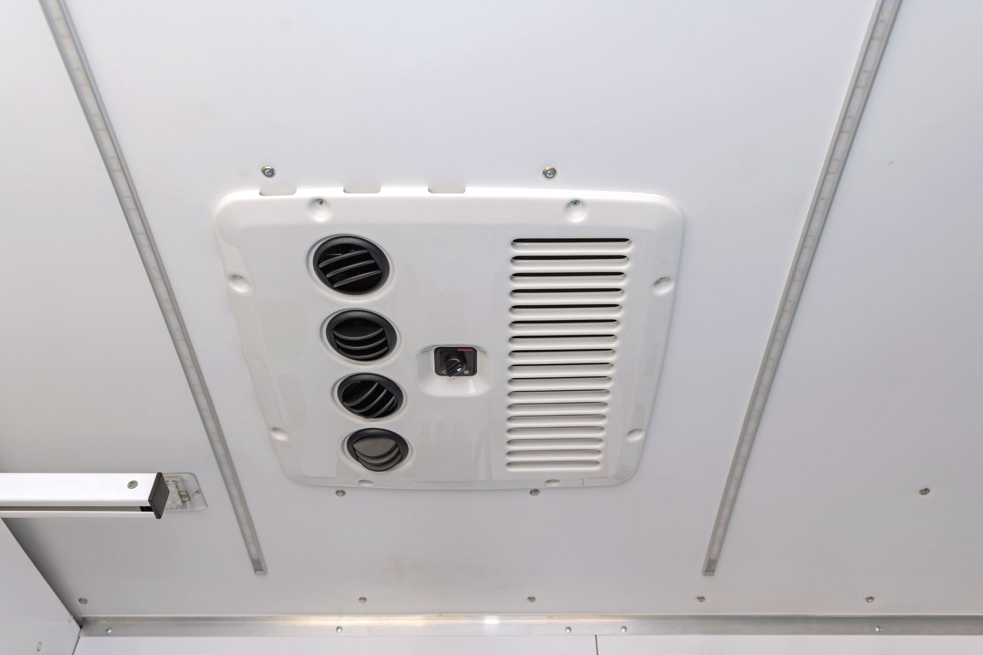 Ceiling-mounted white ventilation panel with three black vents and a louvered grille.