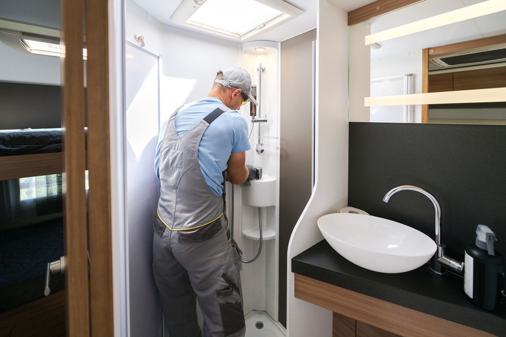 Worker installing a bathroom sink and shower in a compact modern bathroom