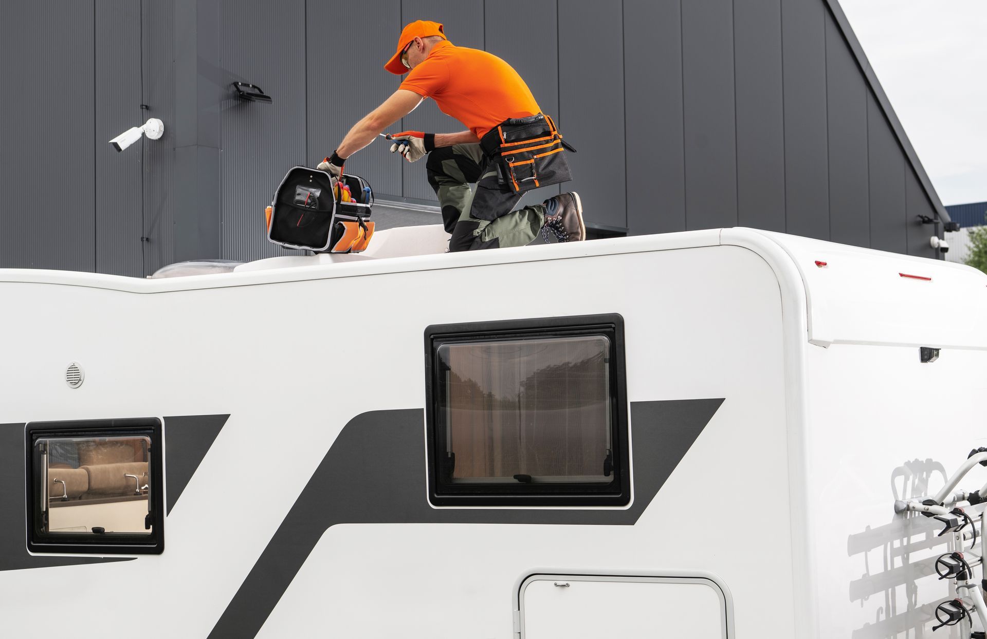 Worker in orange shirt clearing snow from an RV roof with a snowblower