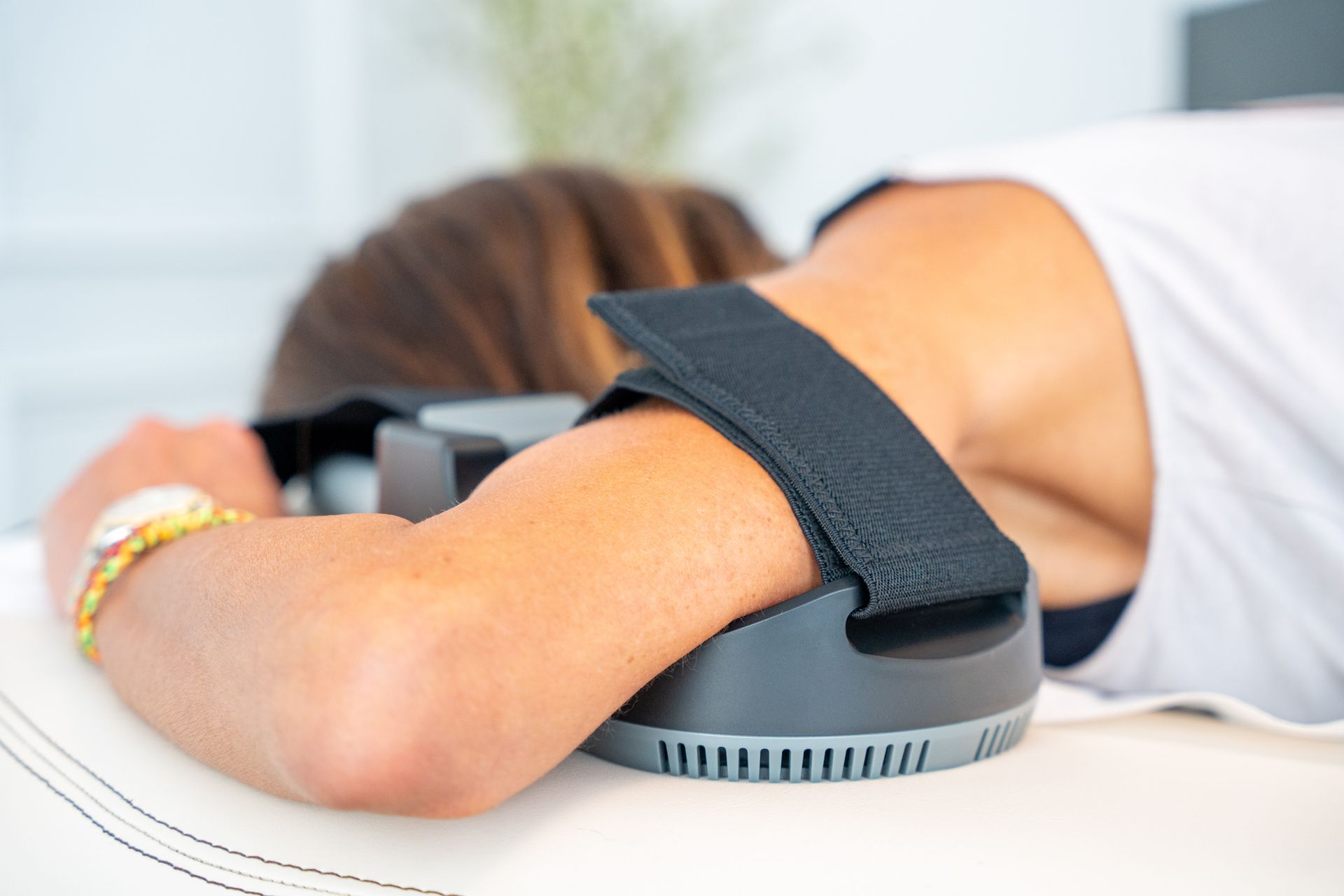 Eine Frau liegt mit einem Gerät am Arm auf einem Bett.