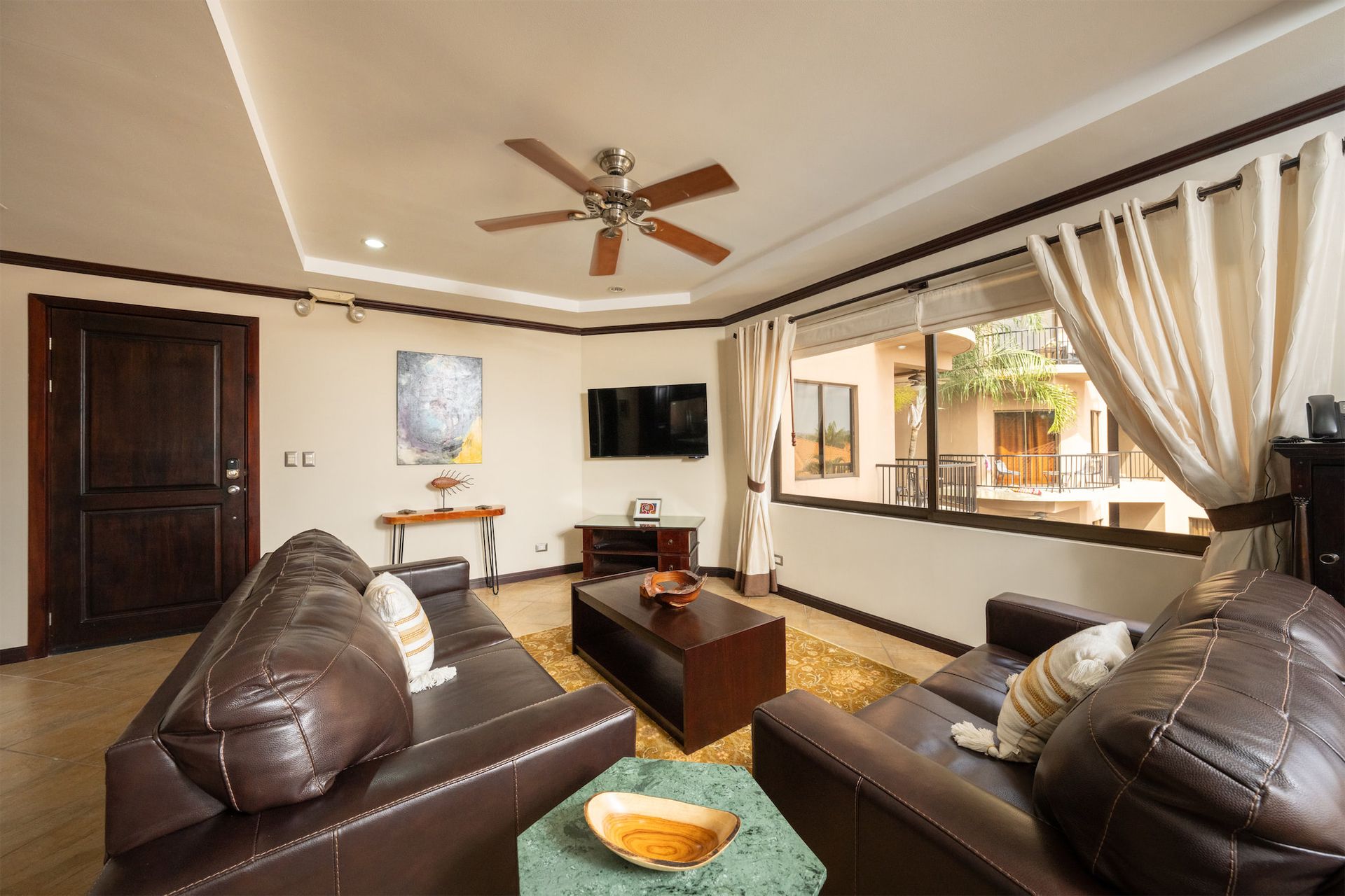 A living room with a ceiling fan and a flat screen tv