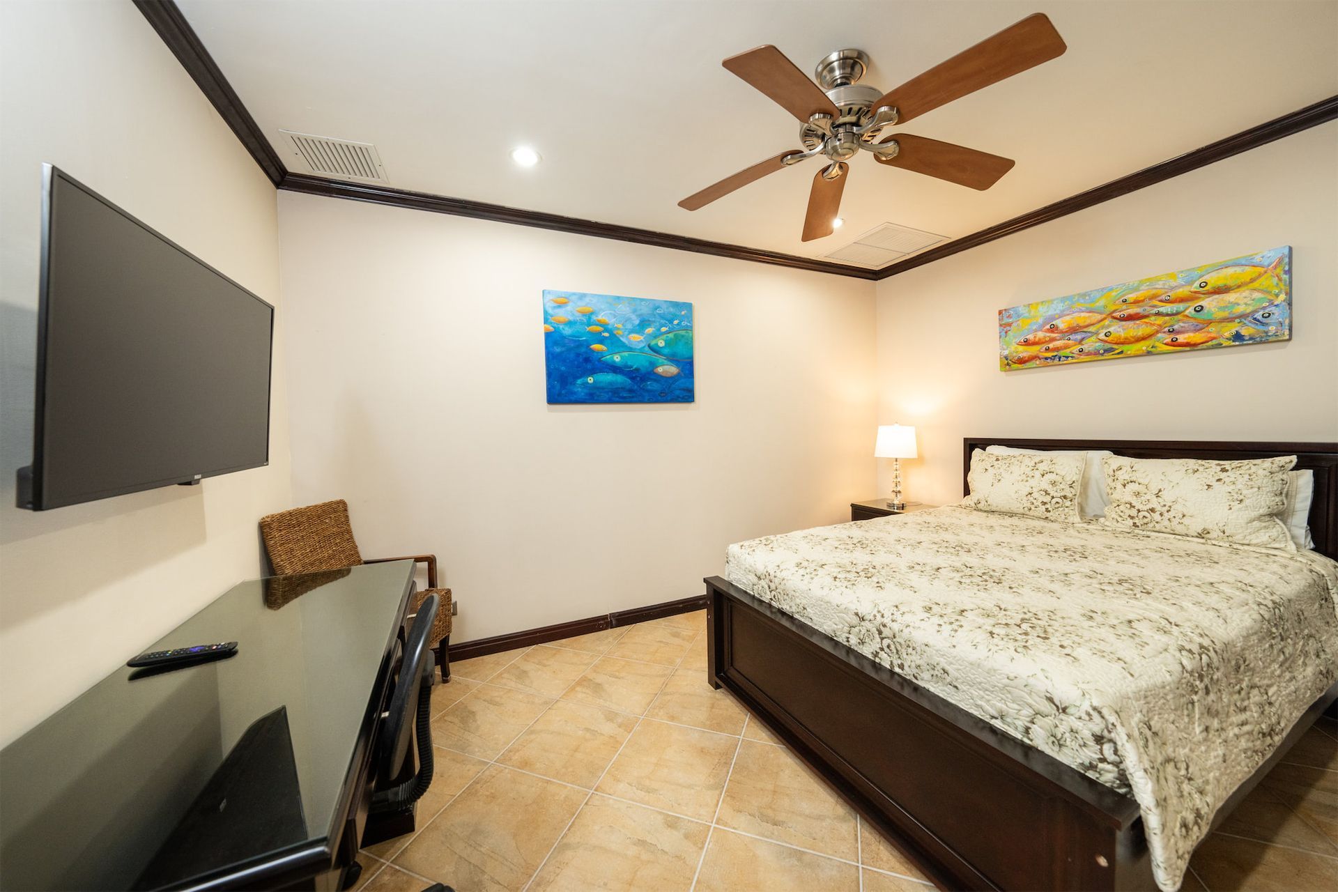 A bedroom with a bed , desk , television and ceiling fan.