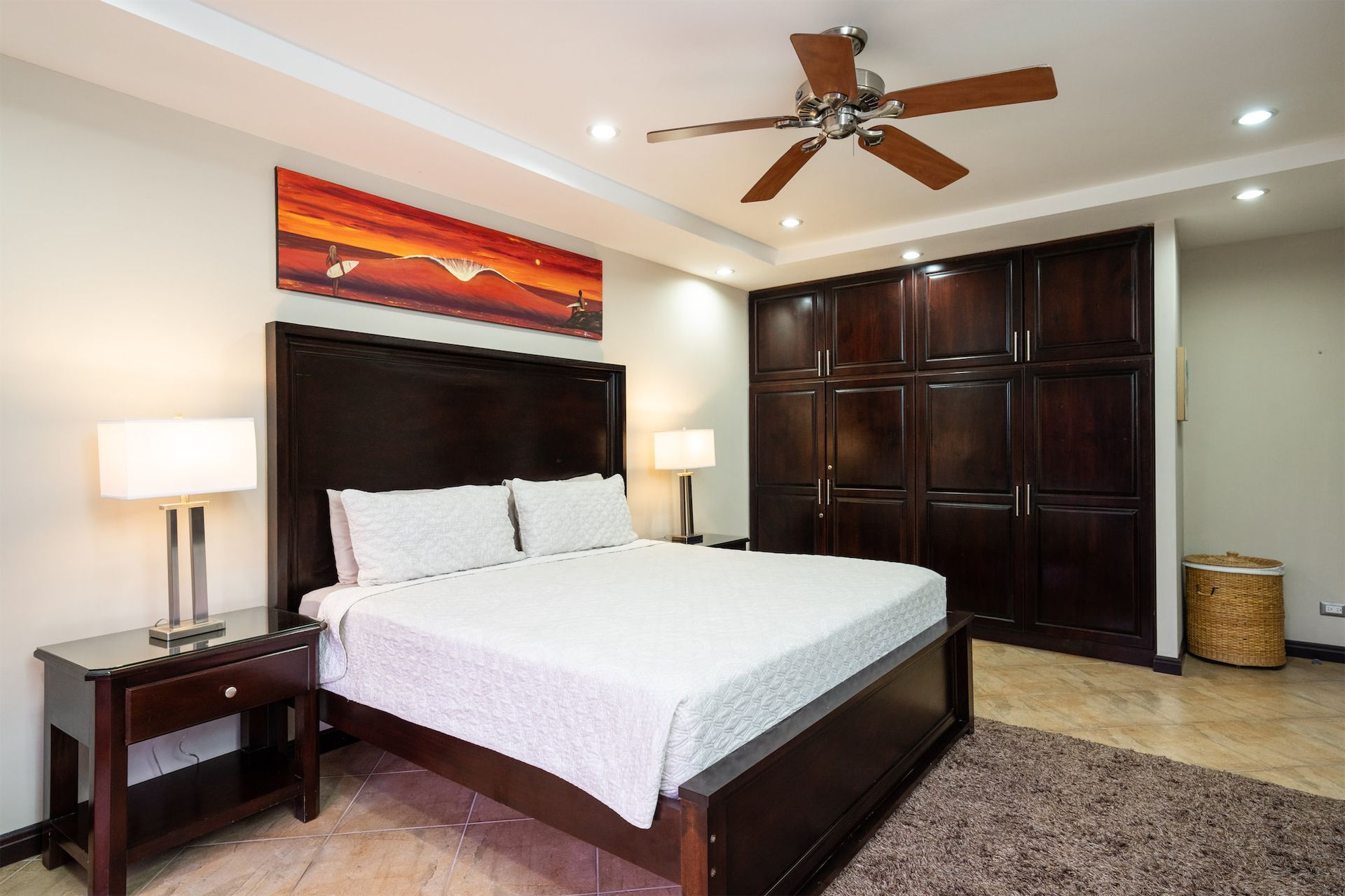 A bedroom with a king size bed and a ceiling fan.