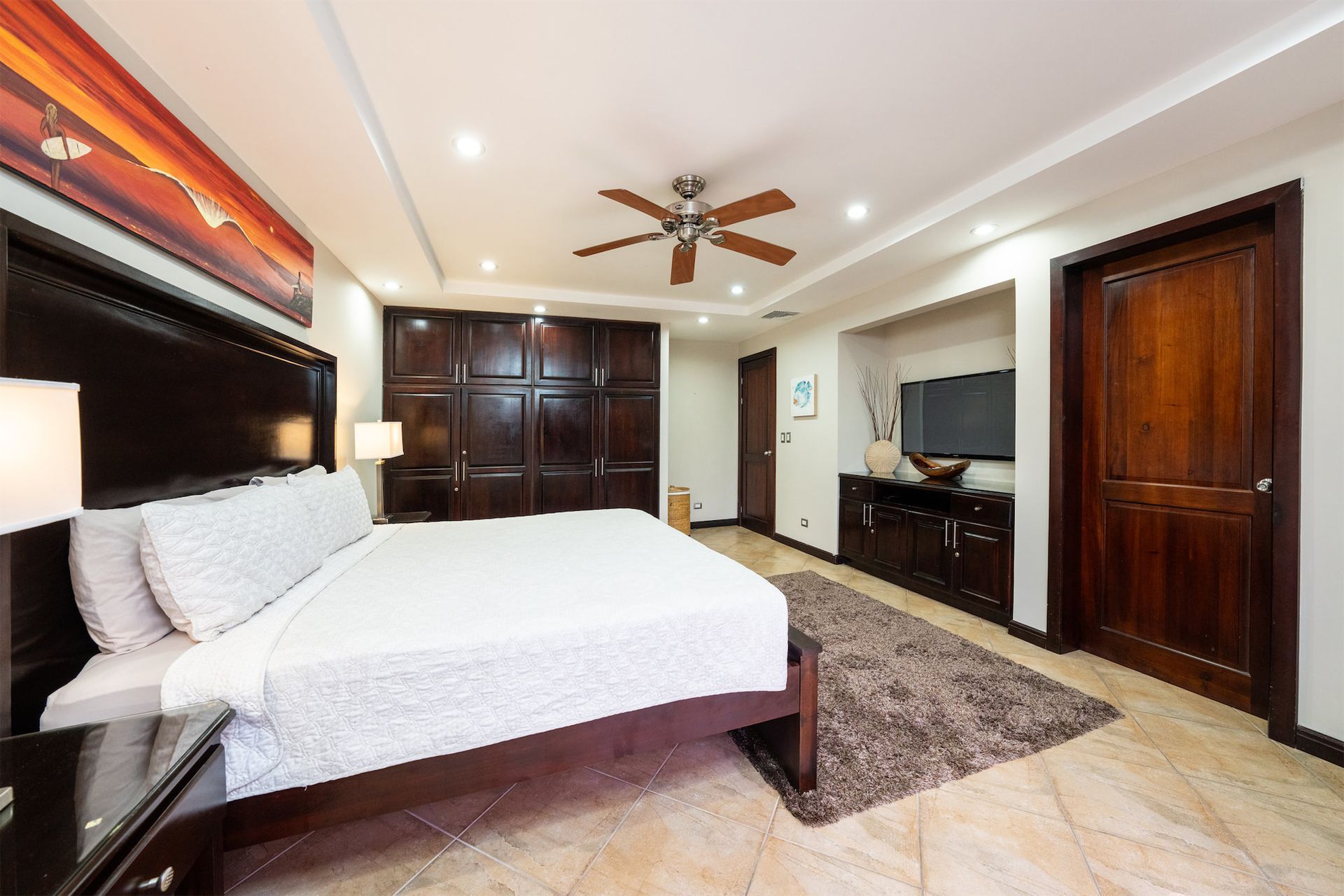 A bedroom with a king size bed and a ceiling fan