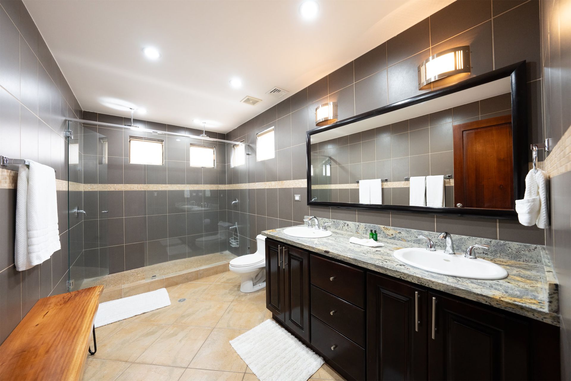 A bathroom with two sinks , a toilet , and a large mirror.