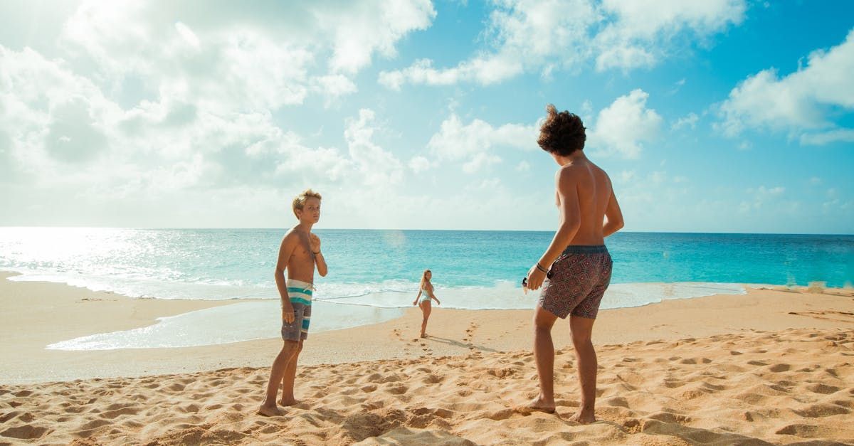 Two boys are playing volleyball on the beach.