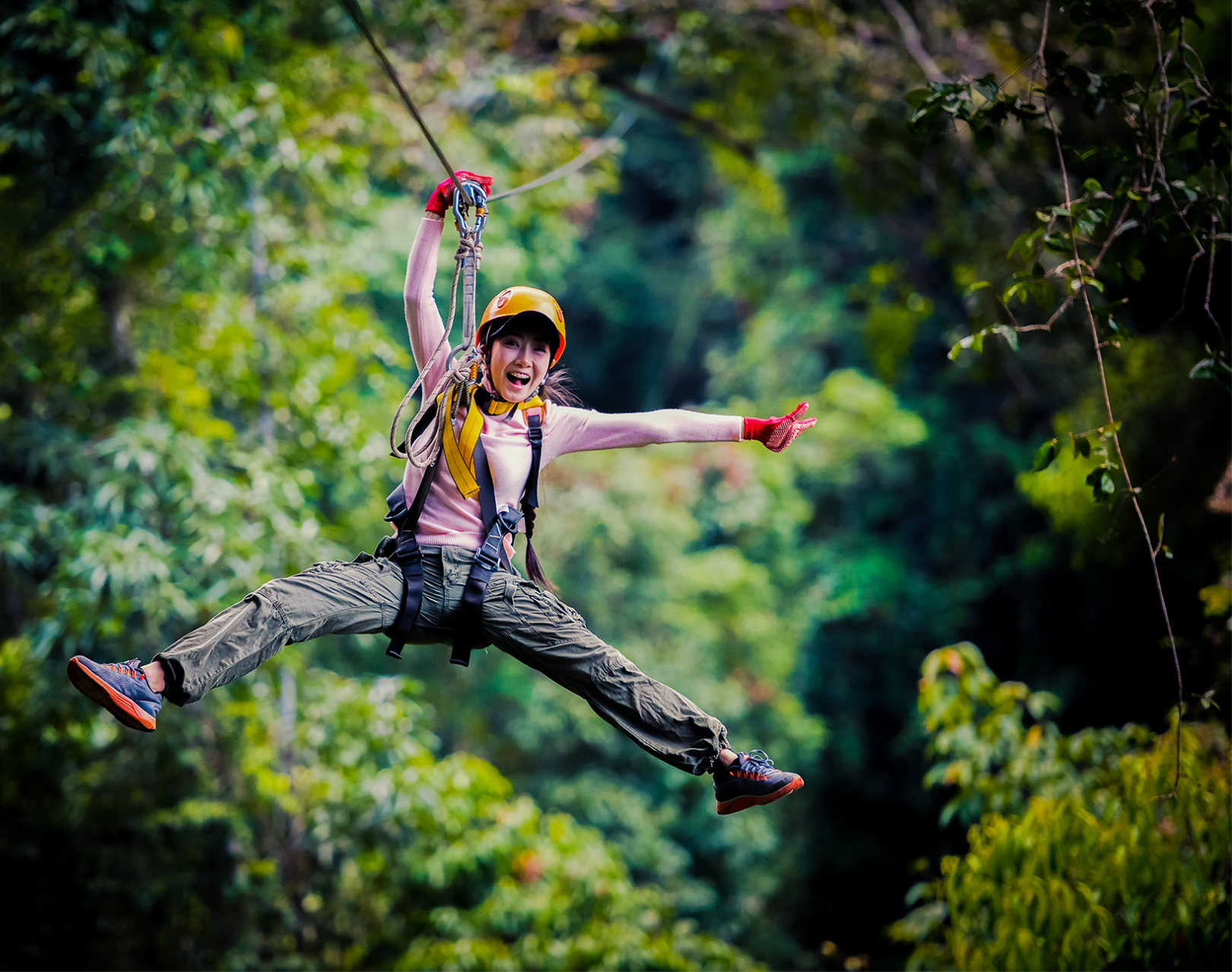 A woman is flying through the air on a zip line.