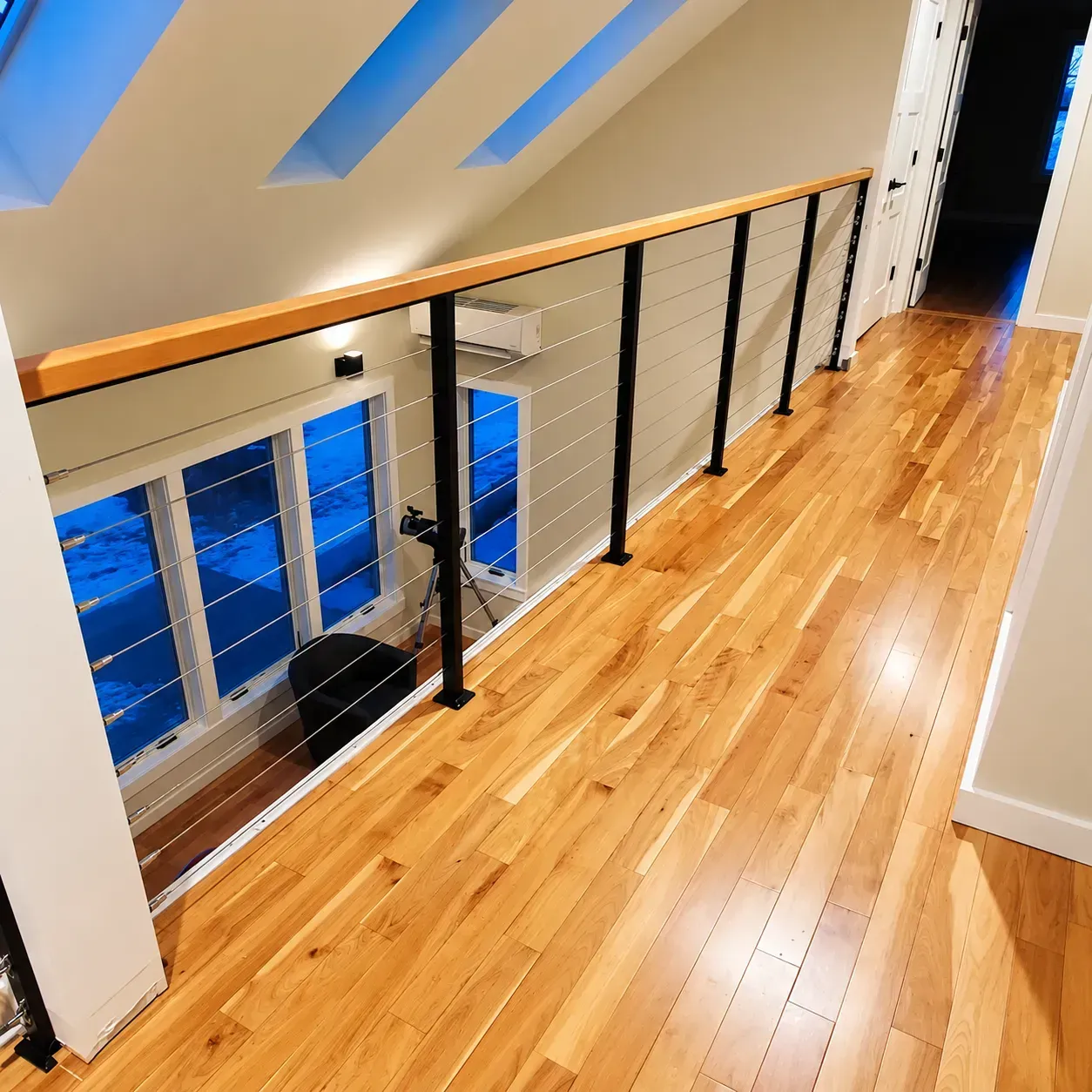 Upstairs hallway with interior cable railing, skylights and a wood floor