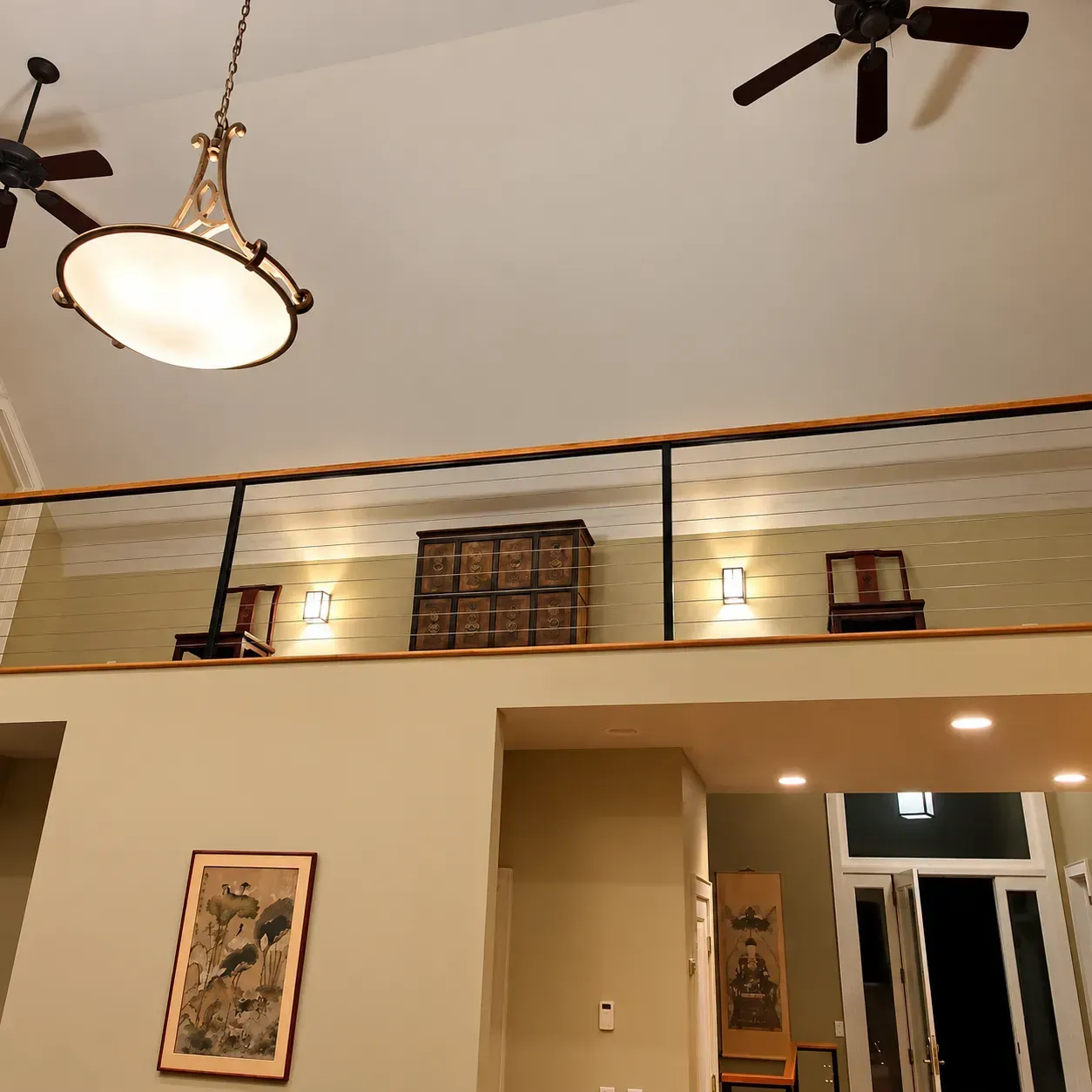 Loft with interior cable railing above a living room with wall lights