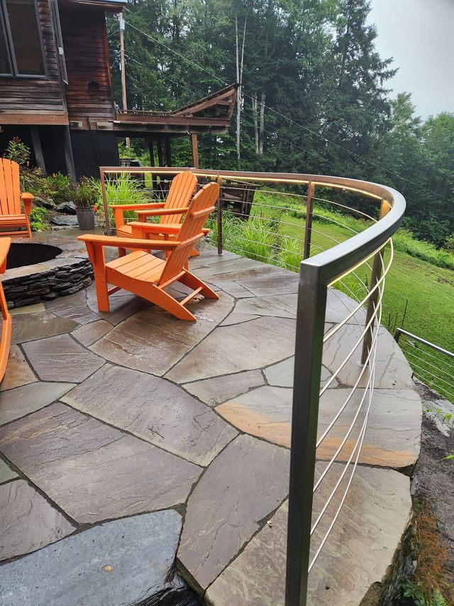 Curved stainless steel railing around a stone patio