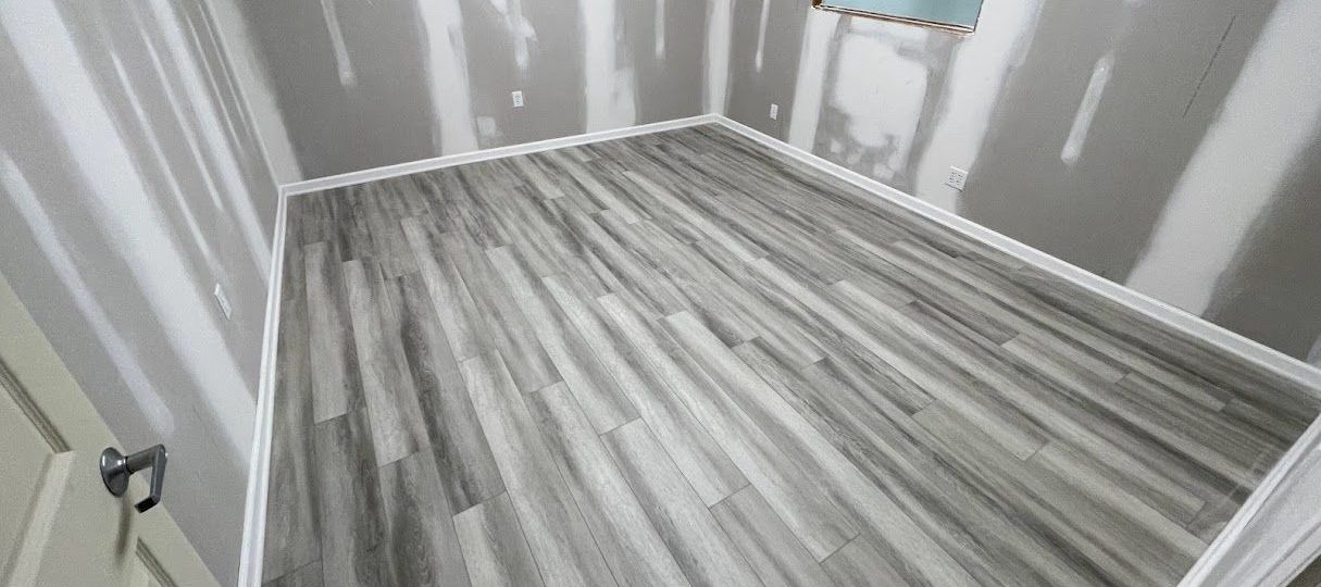 A room with a wooden floor and gray walls.