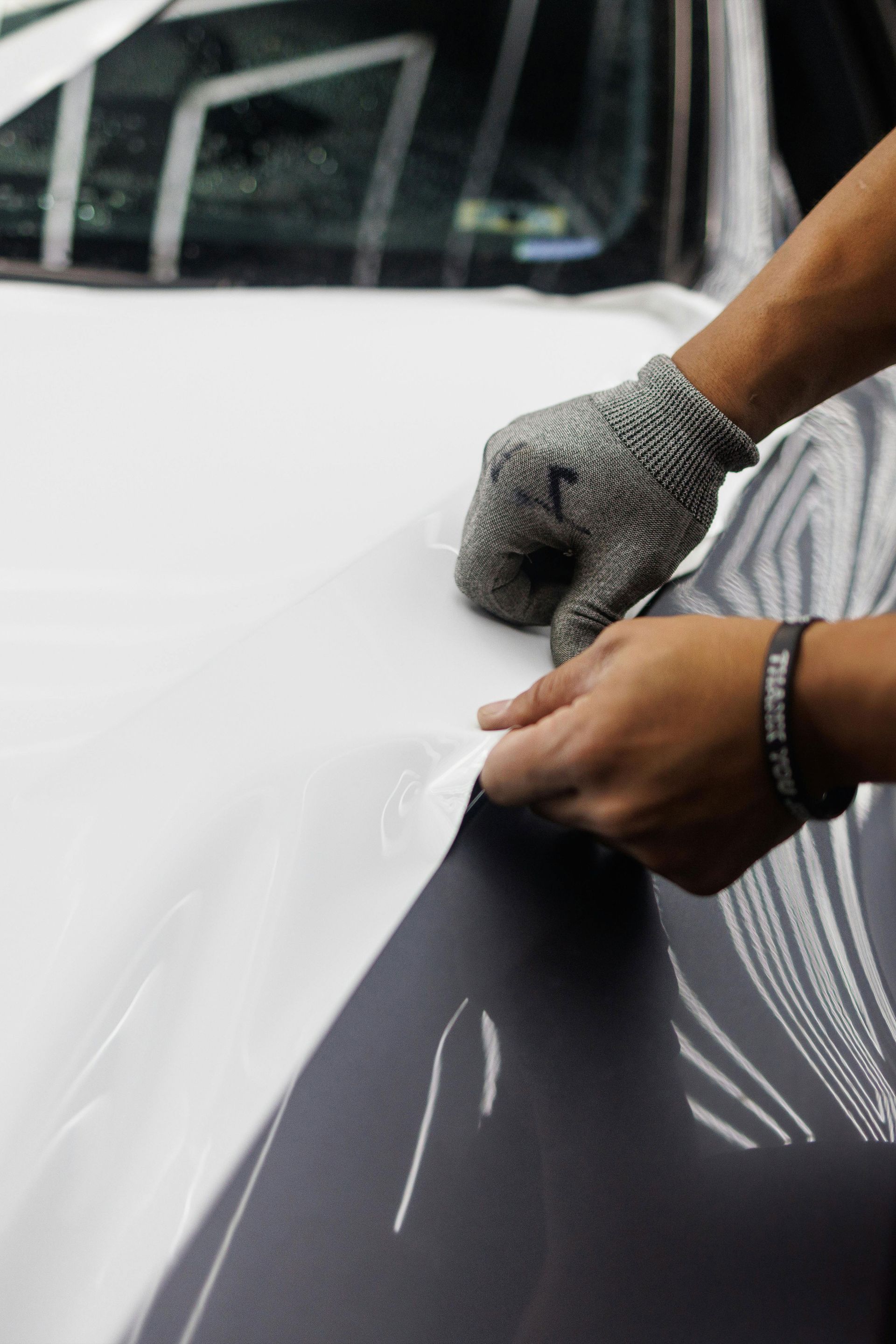 Man cleaning a car hood with soapy water in a garage.