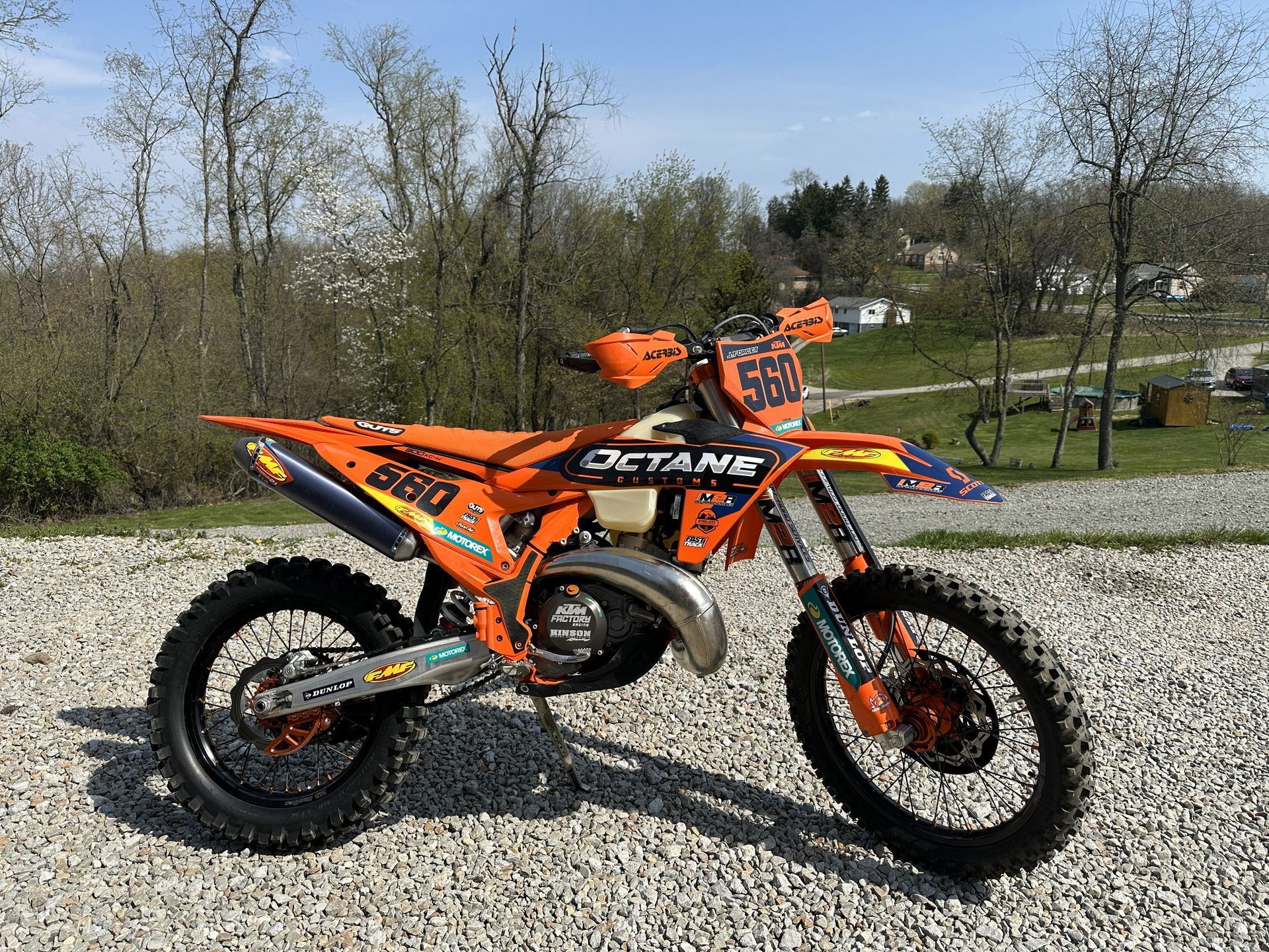 Orange and black dirt bike on gravel, outdoors.