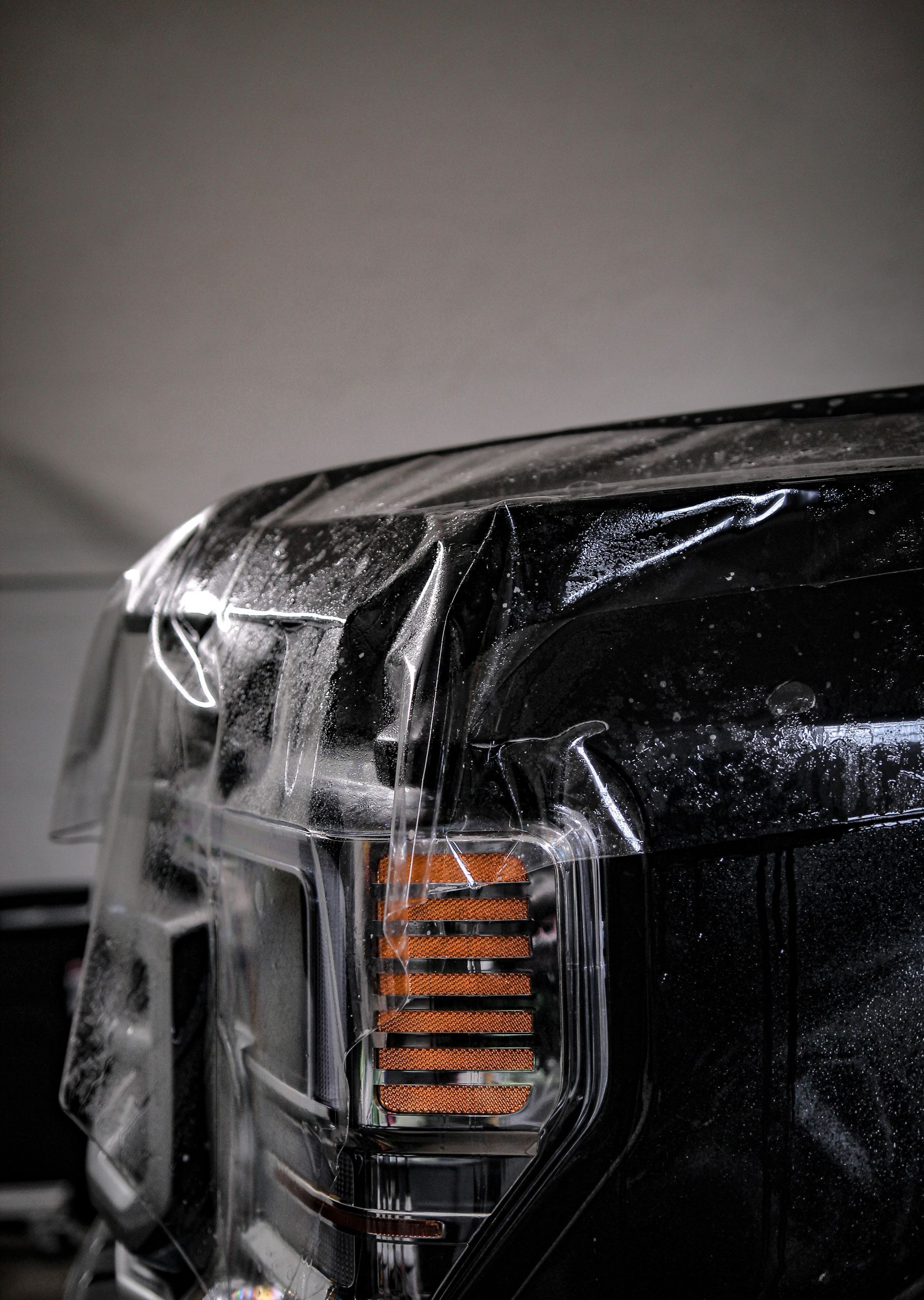 Black truck tail light covered with clear plastic film.
