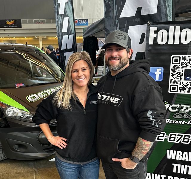 A man and a woman pose next to a car with
