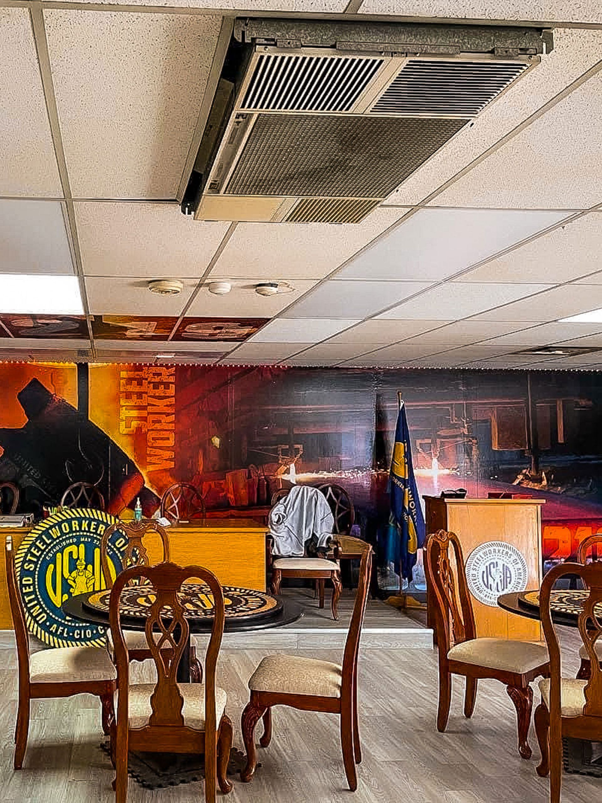 An office interior with chairs, a cityscape mural, and a ceiling air vent.