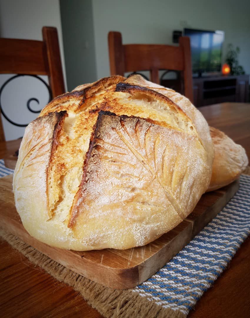 A Loaf of Bread is Sitting on a Wooden Cutting Board on a Table — Atherton Health Food Centre in Atherton, QLD