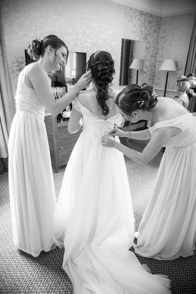 A black and white photo of a bride and her bridesmaids getting ready for her wedding.