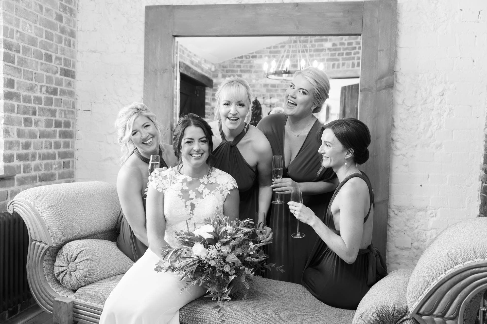 A bride and her bridesmaids are posing for a picture in front of a mirror.