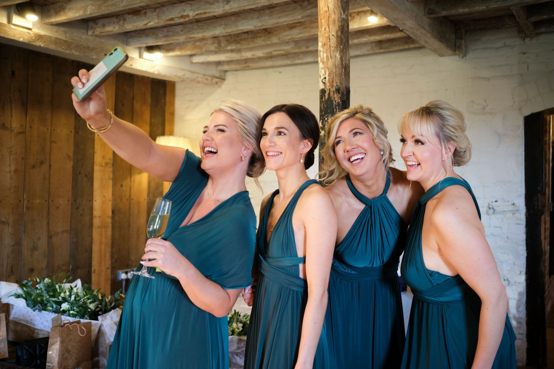 A bride is taking a selfie with her bridesmaids.